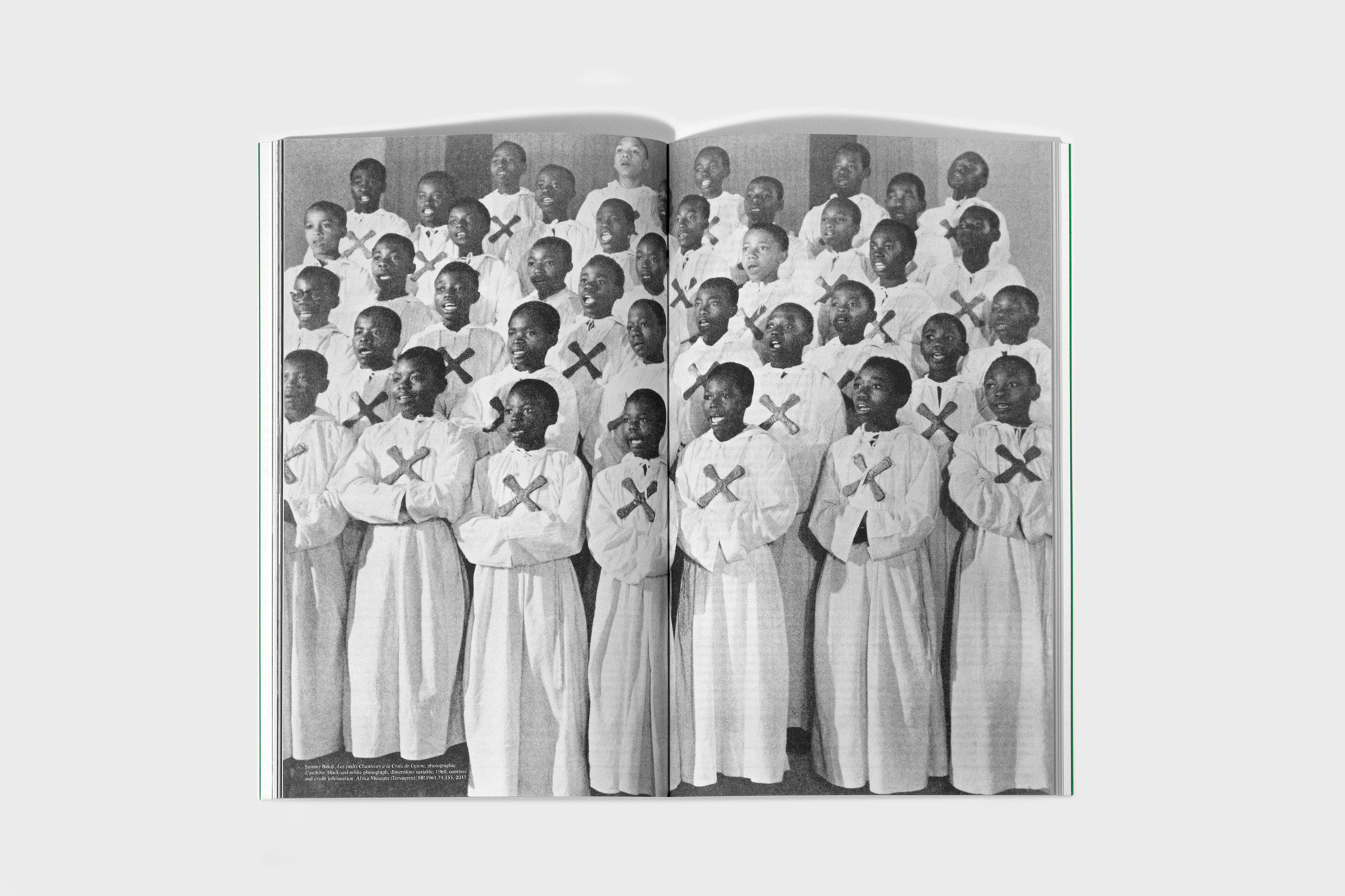 Black and white photograph of a large children's choir in white robes singing indoors, captured in a magazine spread.