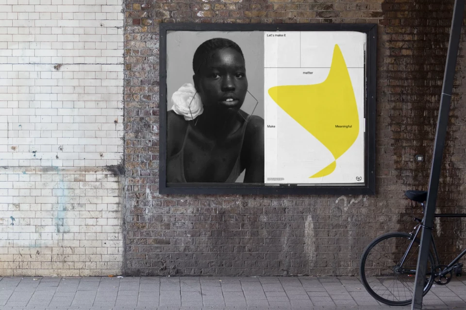Outdoor advertisement featuring a black and white portrait of a woman with a flower next to a poster with a yellow abstract shape.