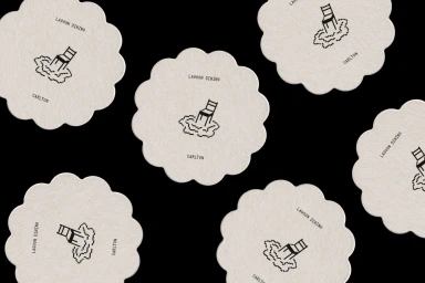 Scallop-edged circular paper coasters featuring pixel art chair illustrations on a solid black background.