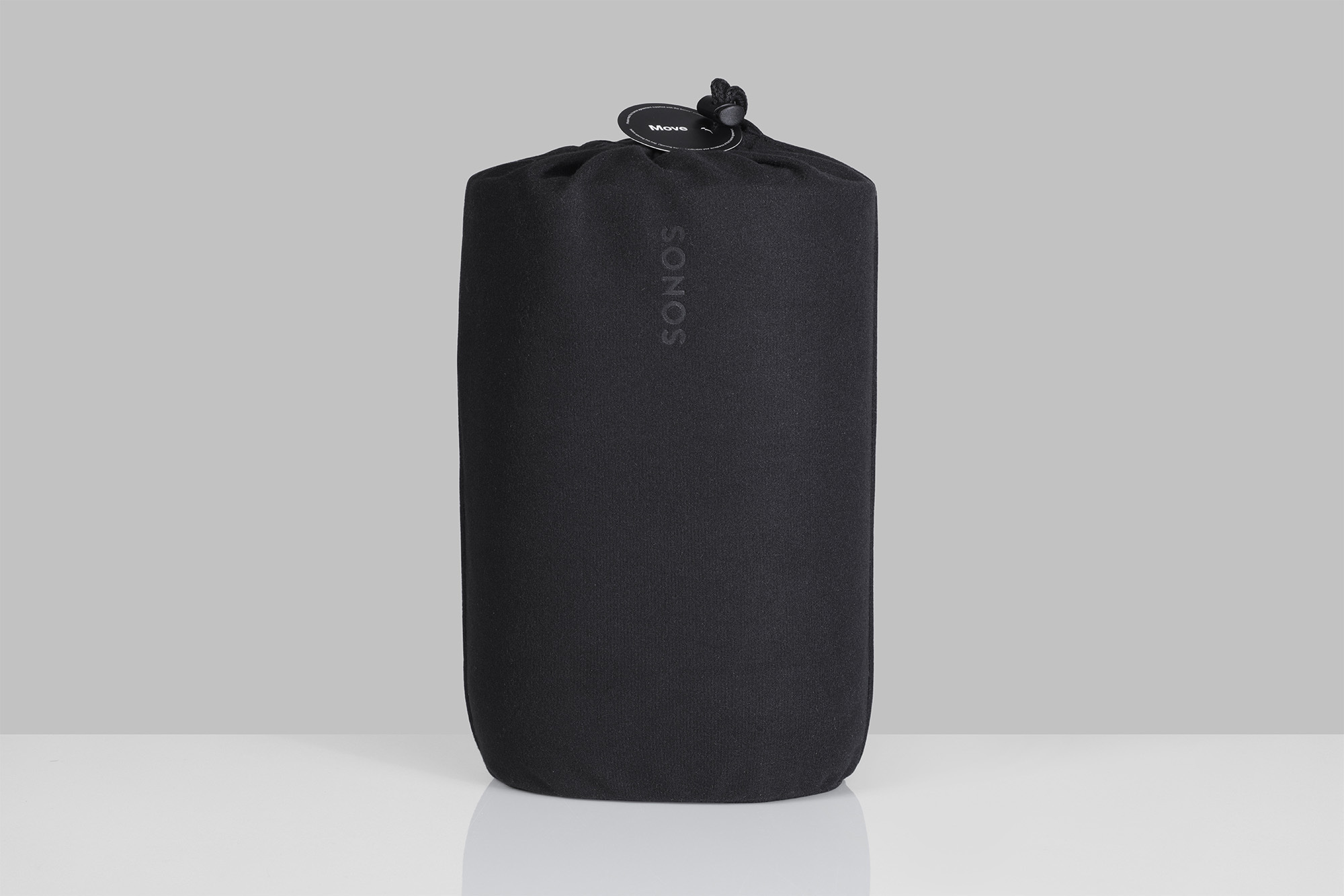 Black Sonos speaker in a drawstring bag against a soft grey background in studio lighting. Minimalist product photography.