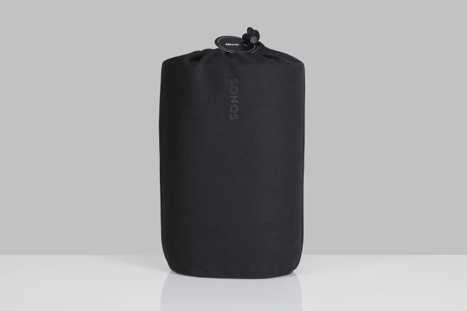 Black Sonos speaker in a drawstring bag against a soft grey background in studio lighting. Minimalist product photography.