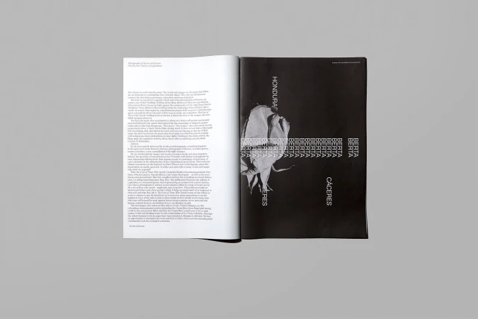 Open magazine with a striking black and white image of a flower next to text-filled pages, spread against a neutral gray background.