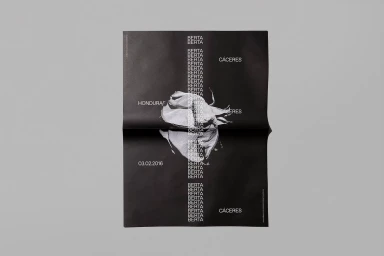A black poster featuring repeated white typography and a central monochrome image of a rose, displayed on a grey surface.