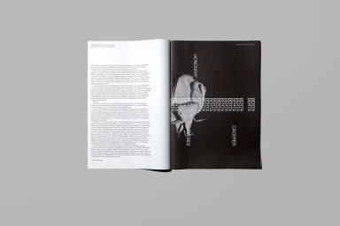Open magazine spread displaying typographic layout and black and white photography on a neutral grey background