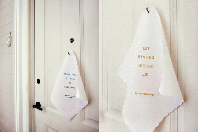 Two white 'Do Not Disturb' signs hang on closed white doors, one reading 'Cleanliness is Next to Godliness' in blue script.
