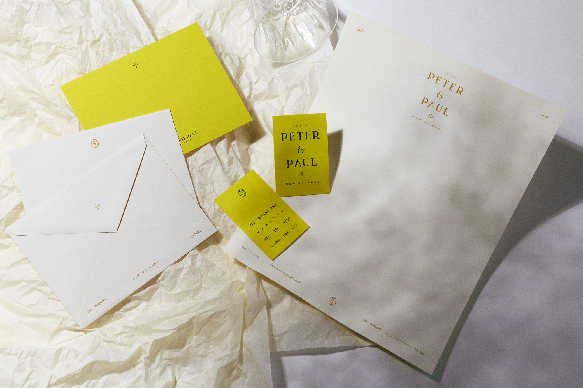 Hotel Peter and Paul stationery set featuring business cards, letterhead, and envelopes in white and yellow tones on crumpled paper.
