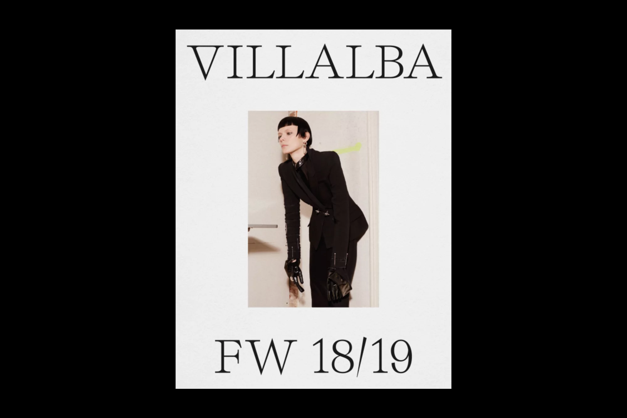 Fashion model posing in a black suit, photographed in a brightly lit interior, for a Villalba FW 18/19 advertisement.