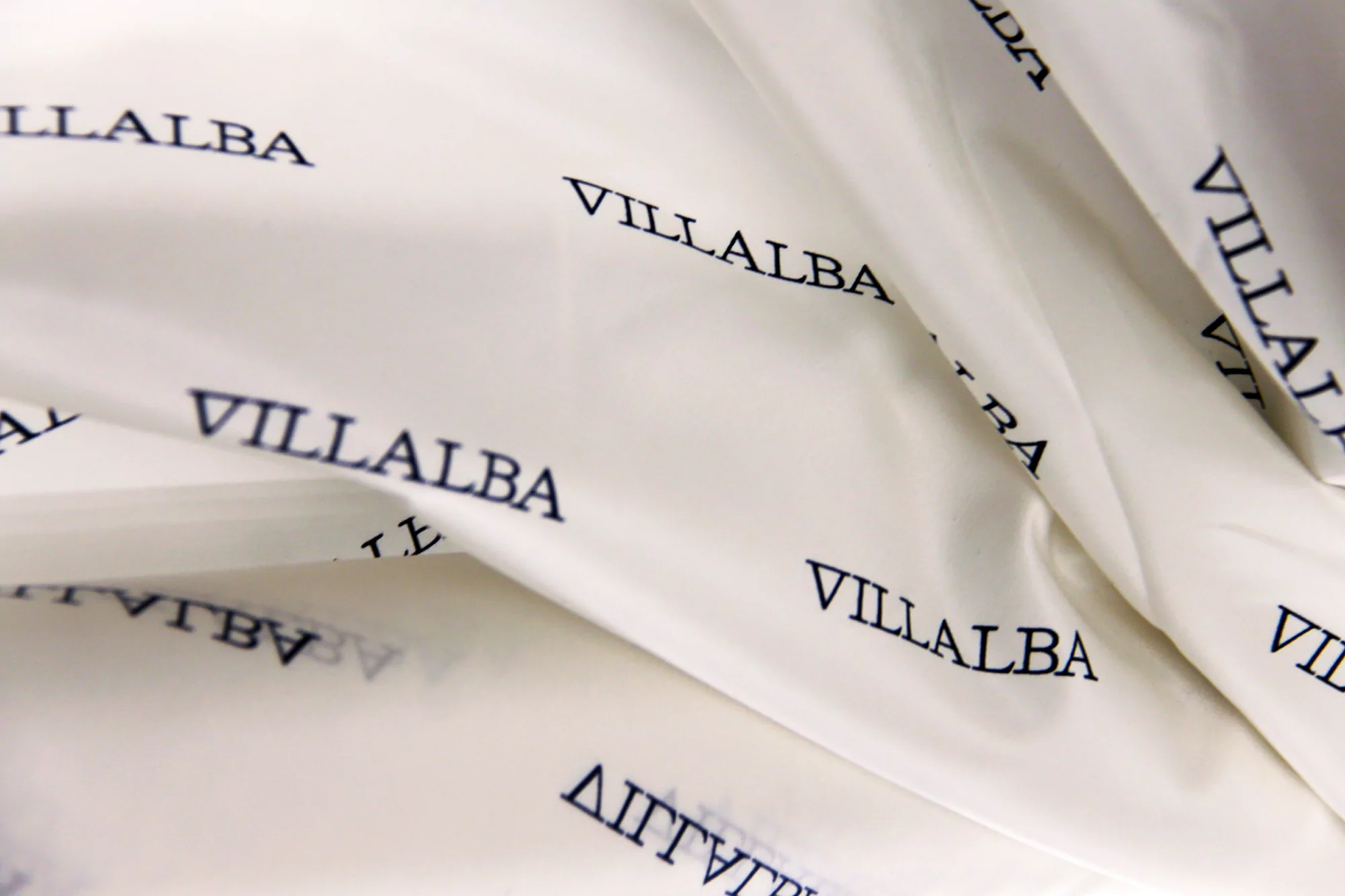 Close-up of wrinkled white material with the repeated black text 'VILLALBA' across the surface.