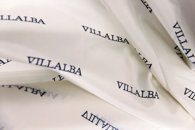 Close-up of wrinkled white material with the repeated black text 'VILLALBA' across the surface.