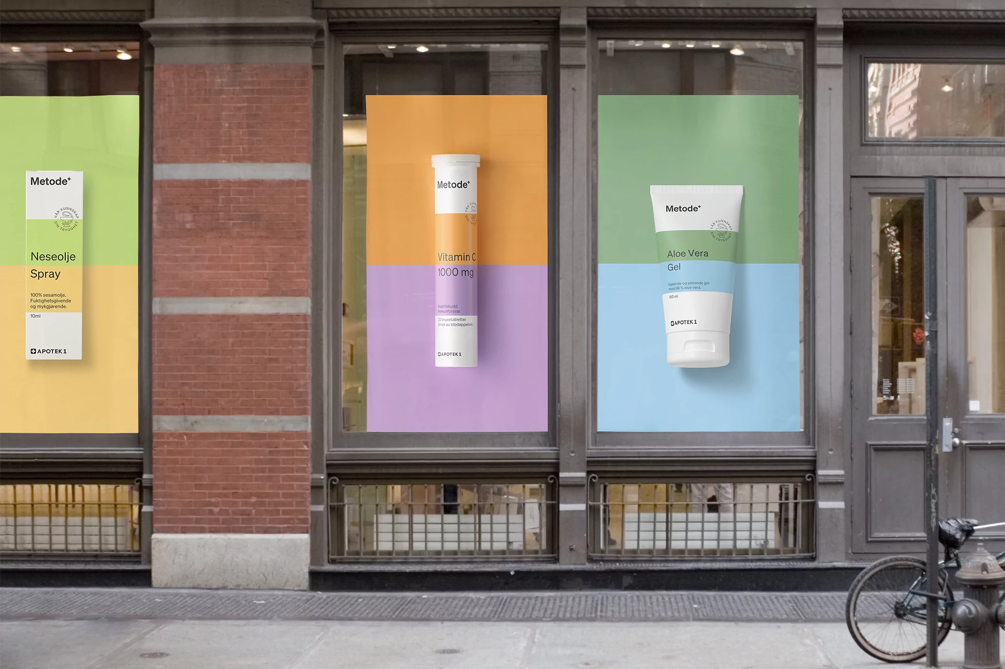 Three posters advertising Methode skincare products displayed in a building window, featuring a bicycle parked on the sidewalk.