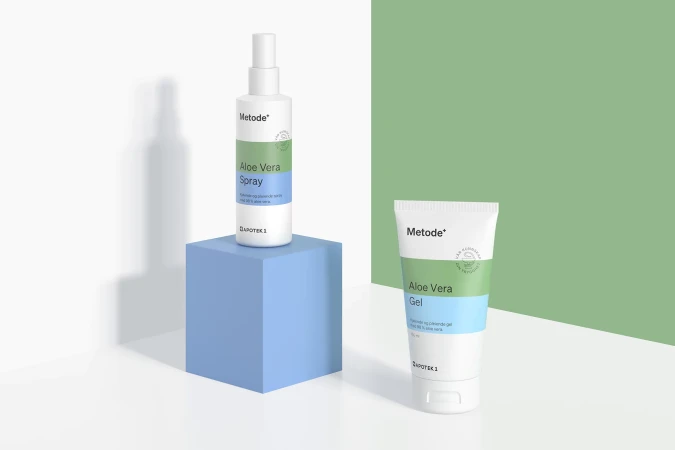 Aloe vera skincare products displayed on blue block against green and white backdrop featuring a bottle and tube.