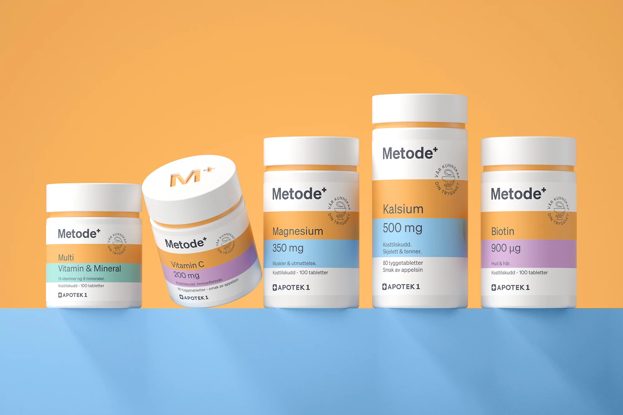 Five bottles of Metode+ vitamins and minerals lined up on a blue surface against an orange background in a studio product shot.