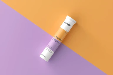 Metode Vitamin C supplement tube angled across a split purple and orange background