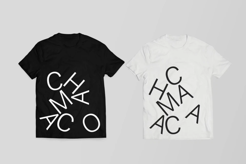 Two t-shirts, one black and one white, display a vertically stacked text design with a casual studio presentation.