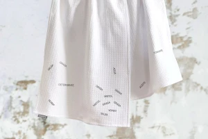 White waffle-weave kitchen towel with printed typography labels against a distressed background