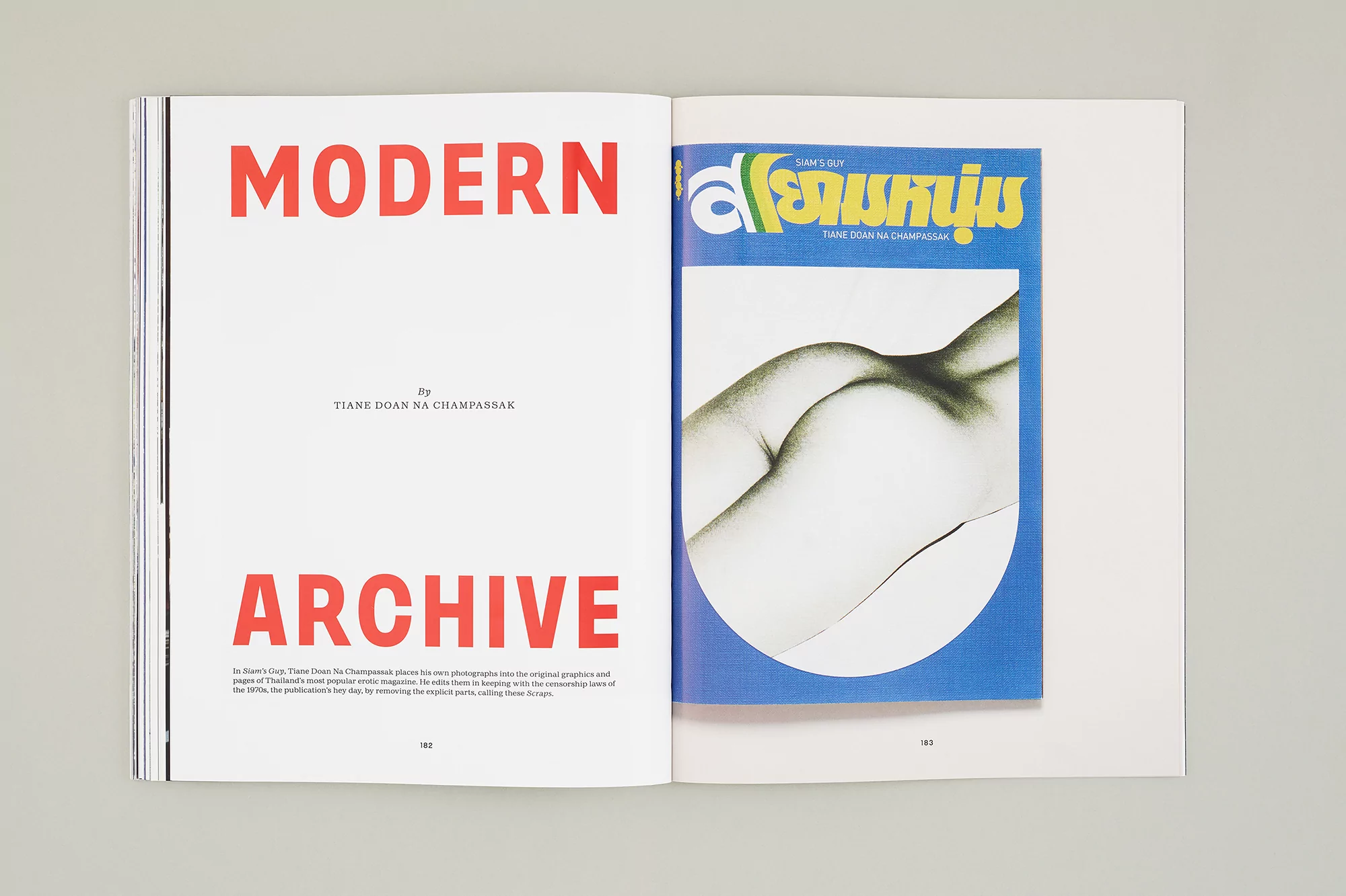 Opened magazine features a nude female back photo against a blue background and red text on white pages on a neutral surface.