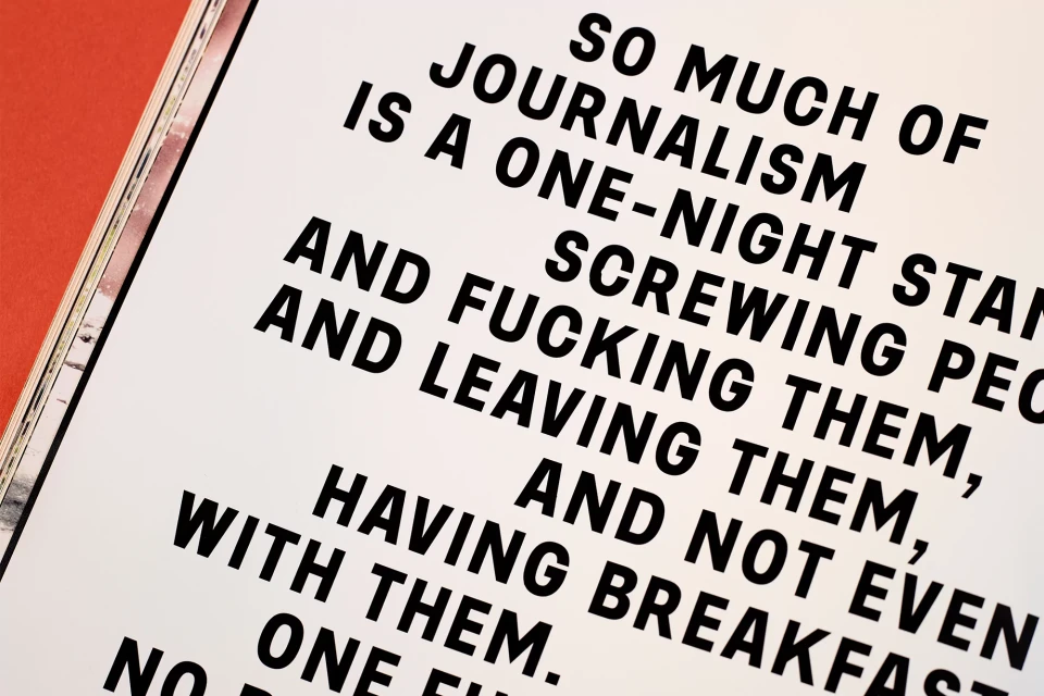 Close-up photograph of black text on a white page, with part of a red-orange book cover visible on the left side of the frame.