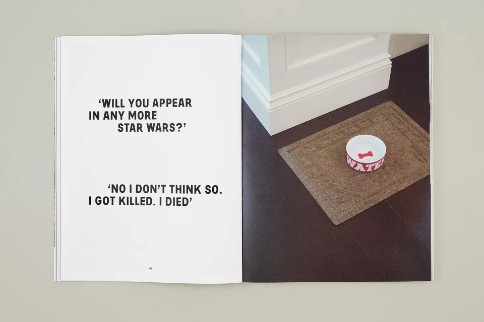 An open book featuring text excerpts on one page and a dog bowl on a floor mat on the other, photographed with indoor lighting.