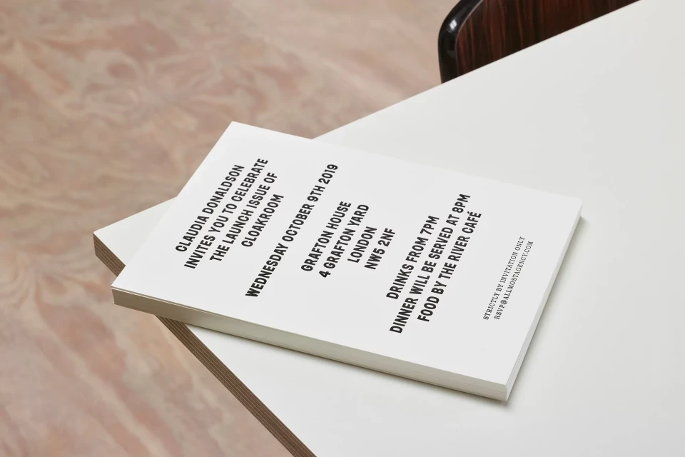 Close-up of event invitation stack featuring event details, including date, venue, and RSVP information on a white table top.