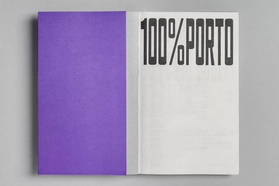 Open book with one purple page and the other with bold black text '100% PORTO' on a gray surface, creating a minimalistic design.