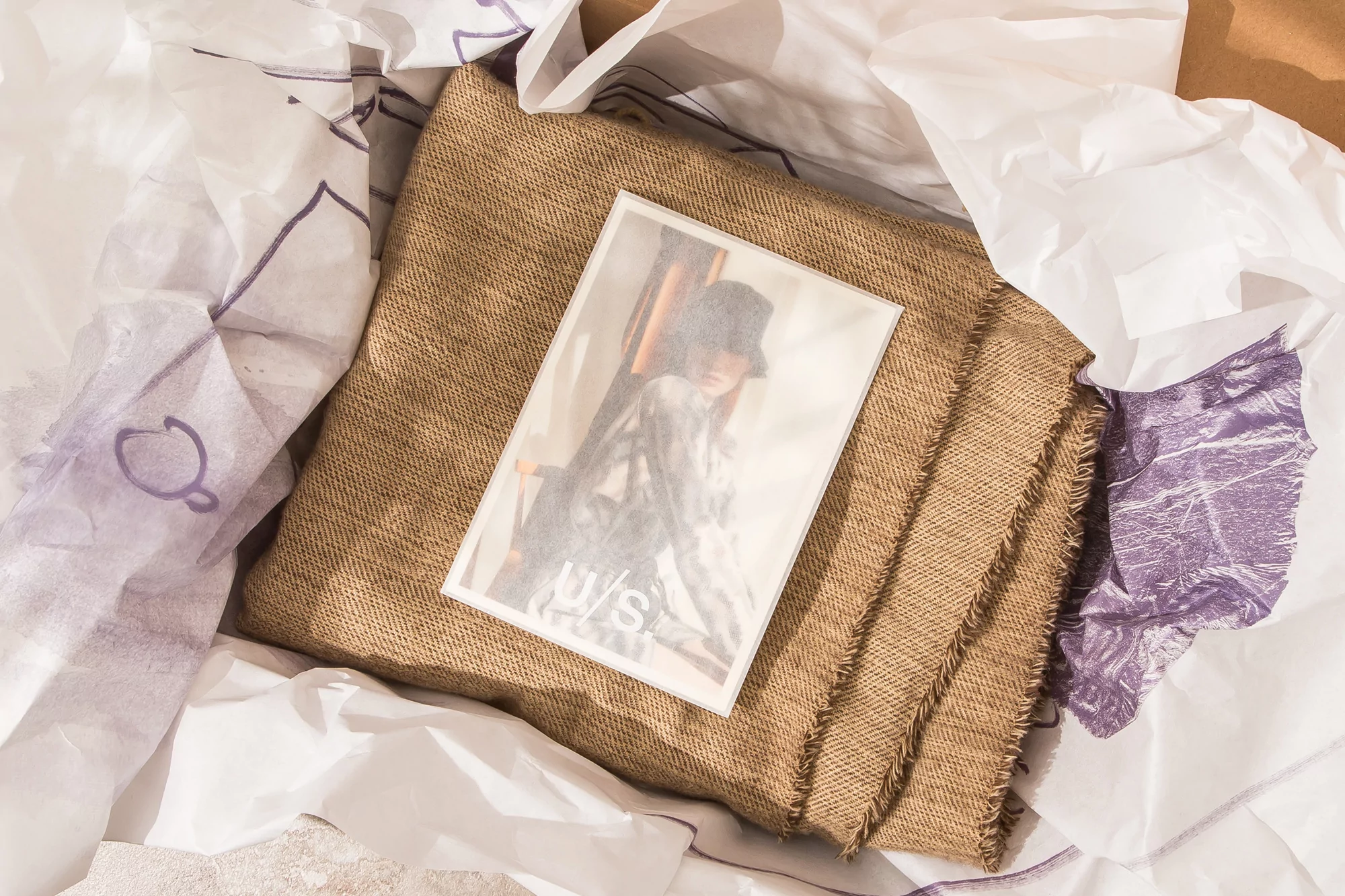 Still life featuring a portrait photo on burlap fabric surrounded by crumpled white paper with faint purple line art details.