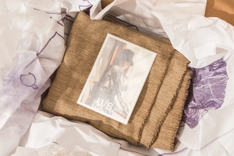 Still life featuring a portrait photo on burlap fabric surrounded by crumpled white paper with faint purple line art details.