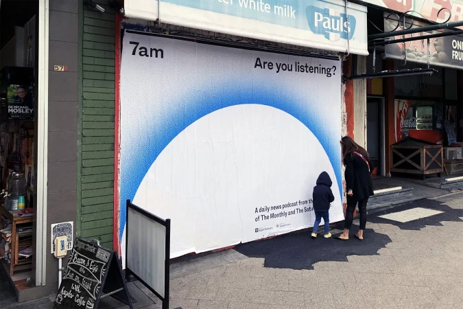 Outdoor ad featuring a podcast promotion, with a woman and child looking at the ad on a building exterior in an urban setting.