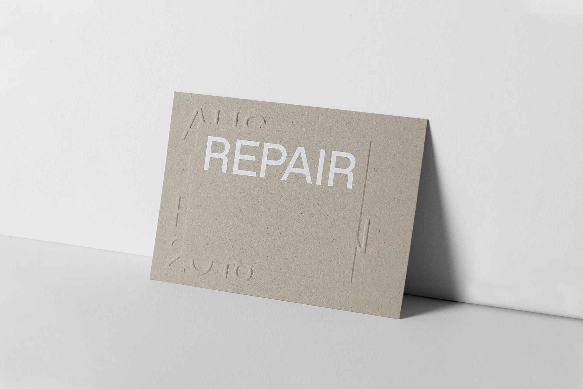 Minimalist design featuring a textured tan card with the word 'REPAIR' in bold white letters against a clean white background.