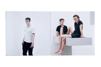 Spreads showing three people against white backgrounds with a man standing and two individuals seated on a raised structure.