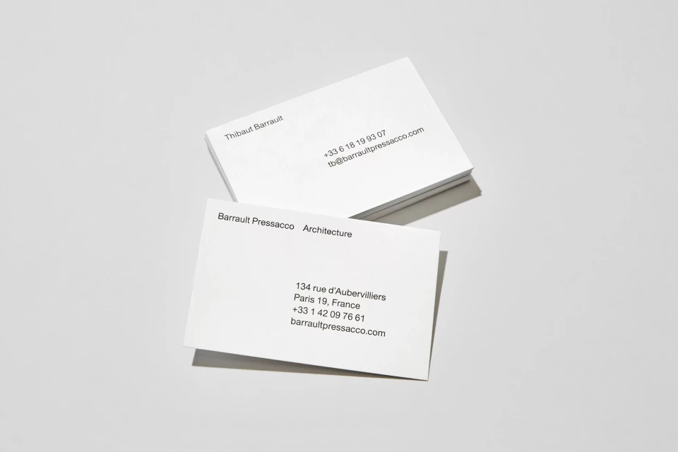 Two stacks of white business cards featuring company and contact information on a white surface in minimalist style.