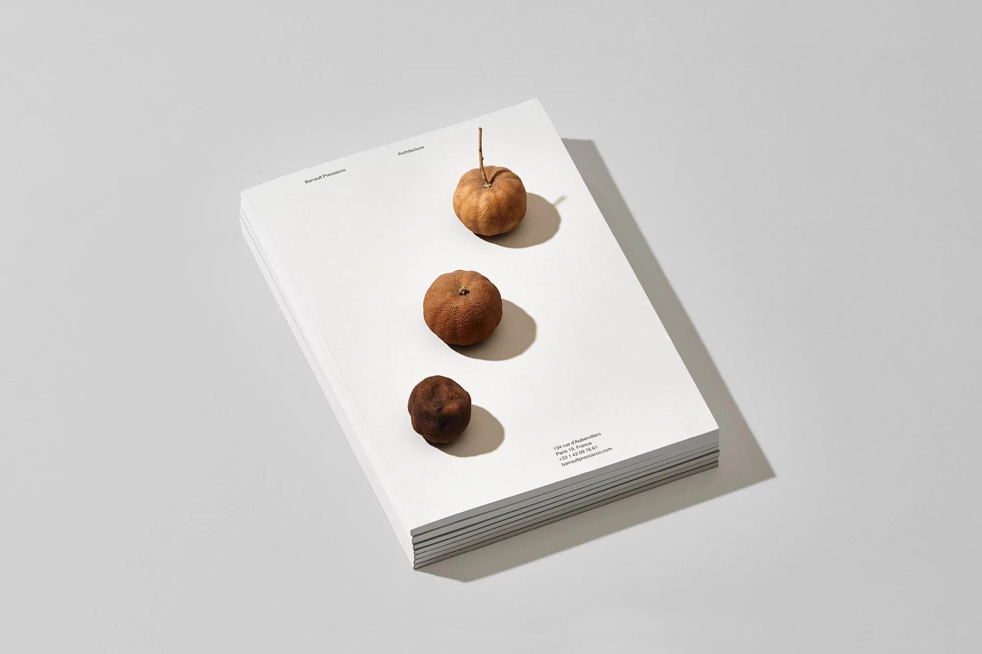 Stack of white paper with three brown, round objects on top in studio lighting. Minimalist aesthetic showcases simple composition and neutral colors.