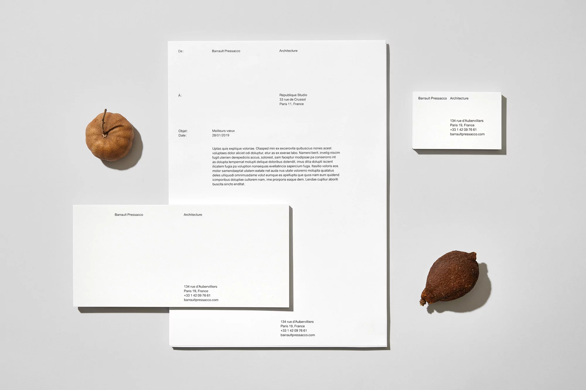 Clean, minimalist architectural stationery mockup featuring a letterhead, business cards, and seeds or nuts on a white surface.