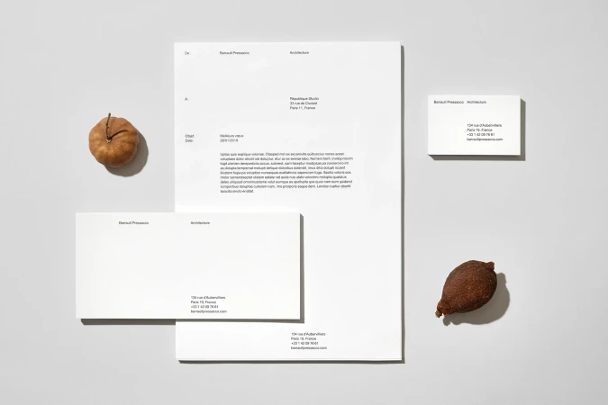 Clean, minimalist architectural stationery mockup featuring a letterhead, business cards, and seeds or nuts on a white surface.