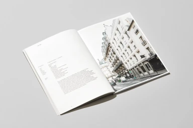 An open magazine lies flat on a light grey surface, displaying architectural photography and typographic layout.