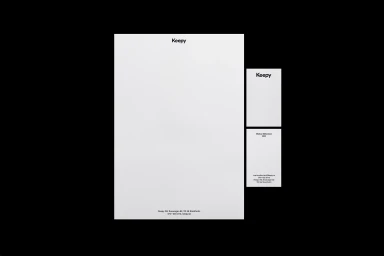 Keepy brand identity stationery set including letterhead and business card on black background.