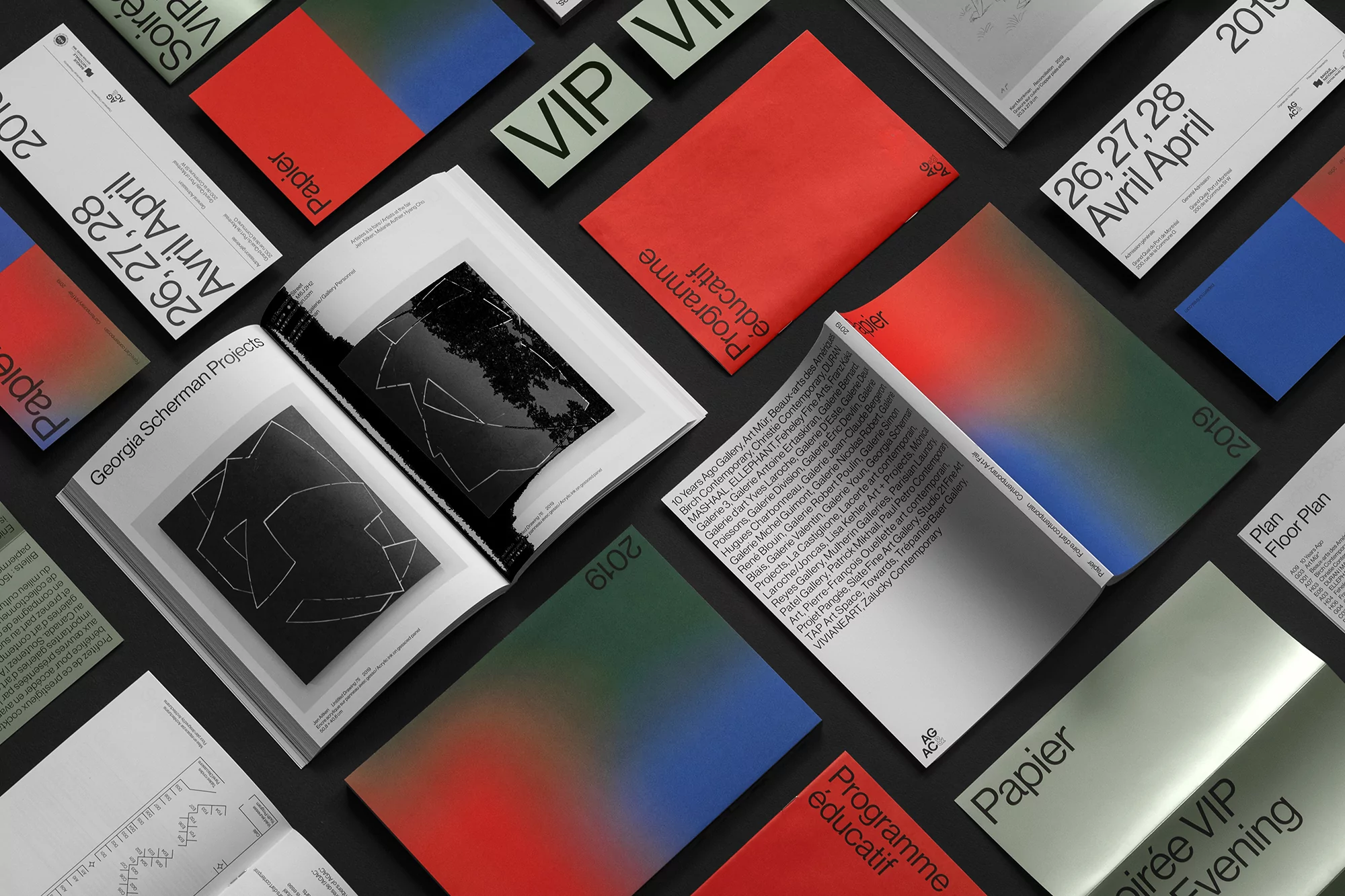Assorted art publications and materials are arranged on a dark surface, featuring various cover designs and open books with artwork.