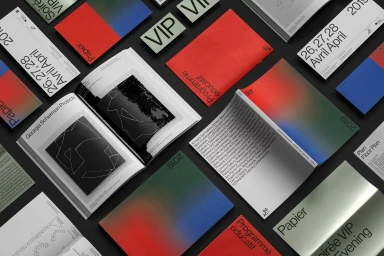 Flat lay arrangement of Papier brand identity collateral including books, brochures, and cards with gradient designs