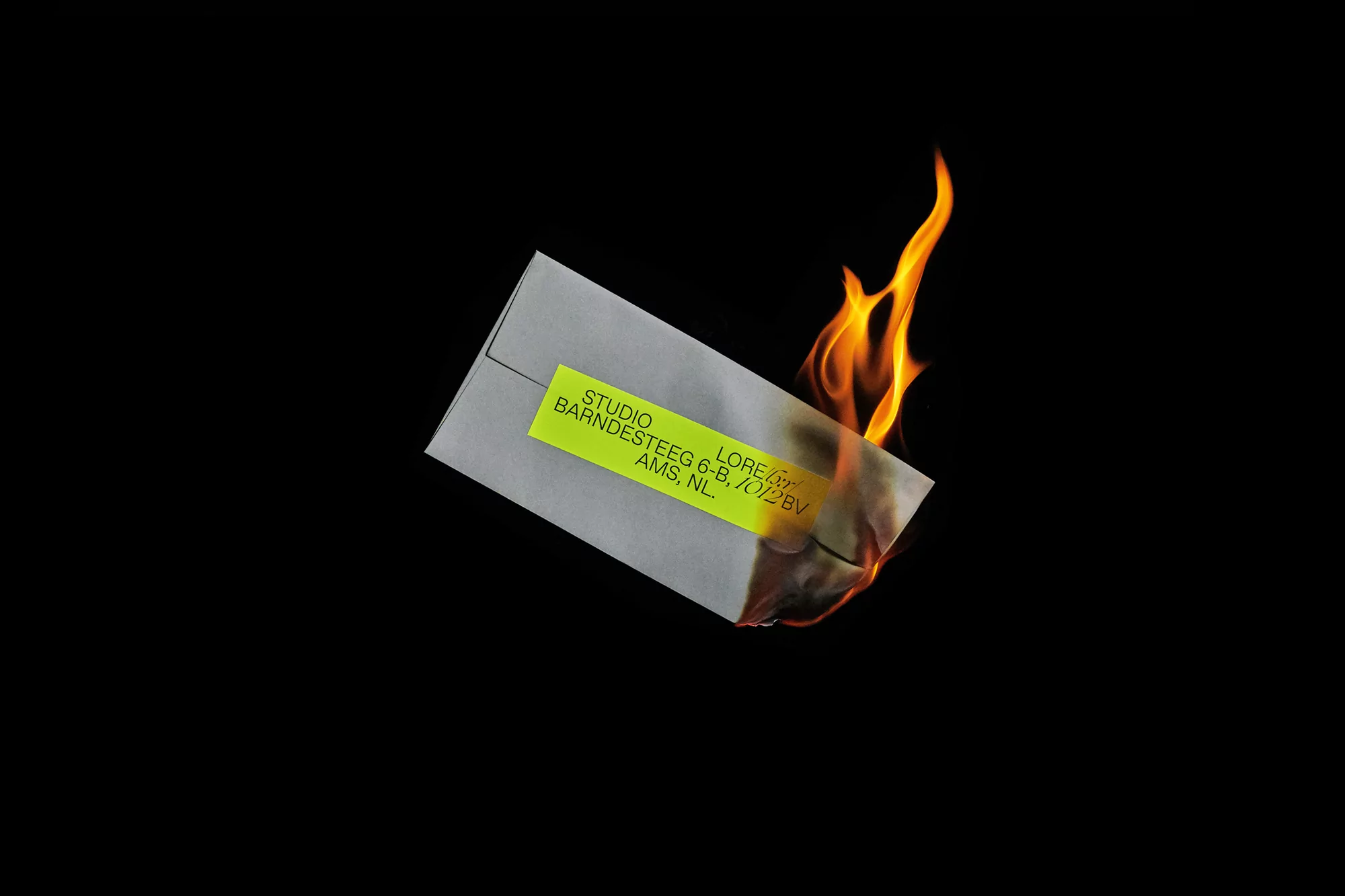 Burning grey envelope with a bright yellow address label set against a dark black background, flames emanating upwards.