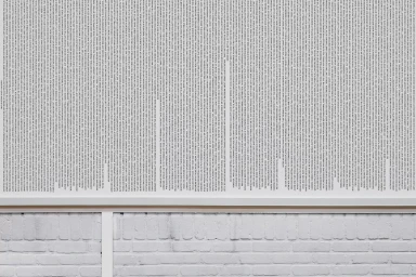 Close-up image of a framed white poster covered in dense blocks of black text, mounted on a white brick wall.