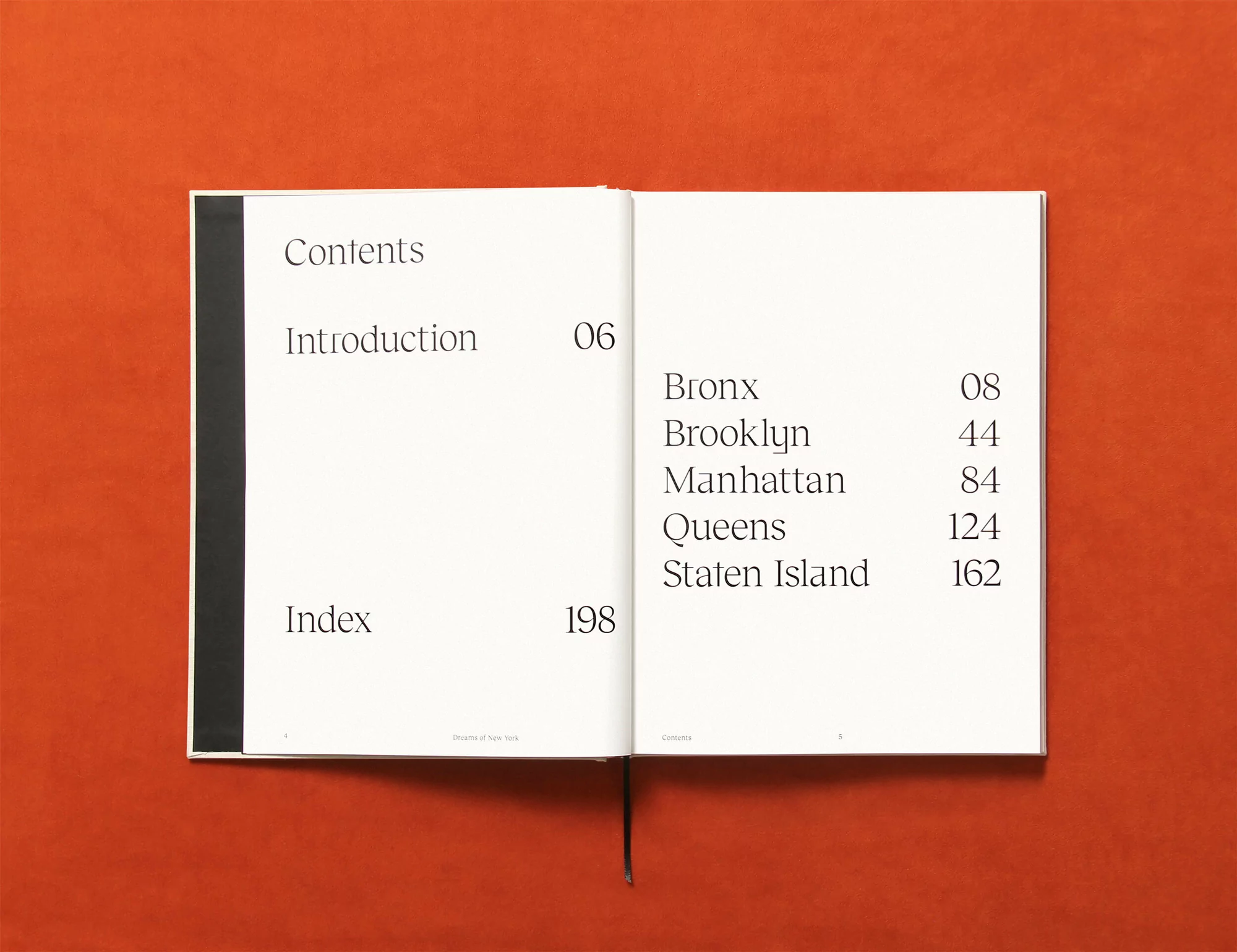 Open book on an orange surface displays 'Contents,' 'Introduction,' 'Index,' and borough names like 'Bronx' and 'Manhattan'.