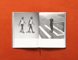 An open book displaying black and white photographs set against a solid orange background