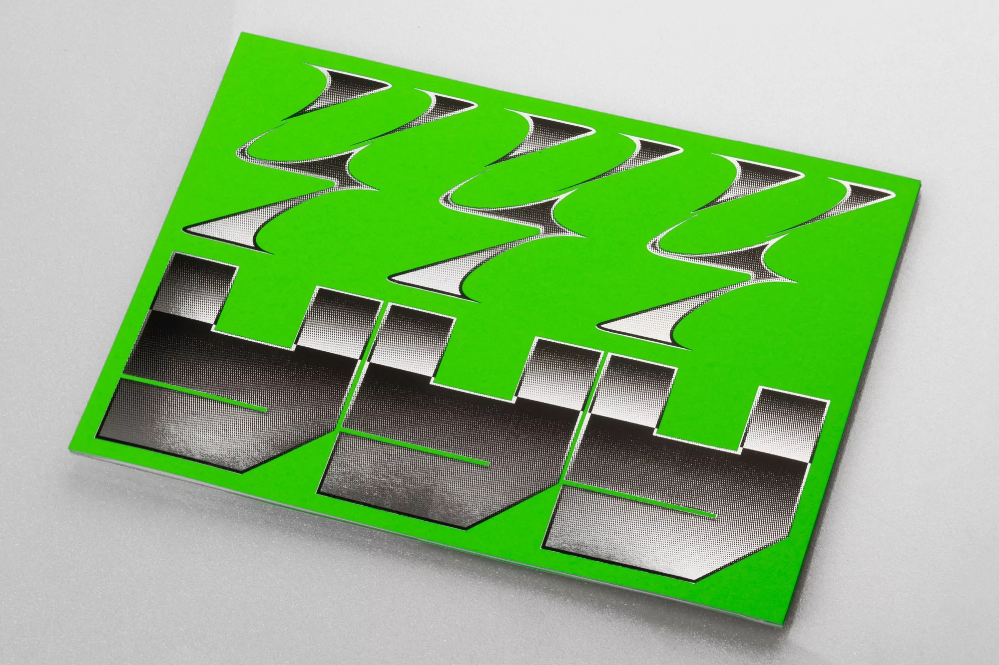 Close-up of a green graphic art sheet with cutout geometric shapes, showcasing a modern and abstract design on a white surface.
