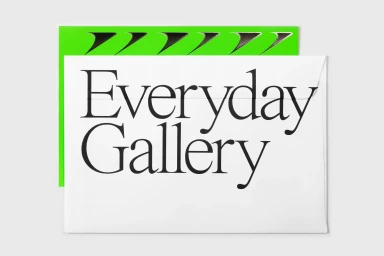 White envelope with black serif typography spelling Everyday Gallery placed over a bright green patterned card against a light grey surface.