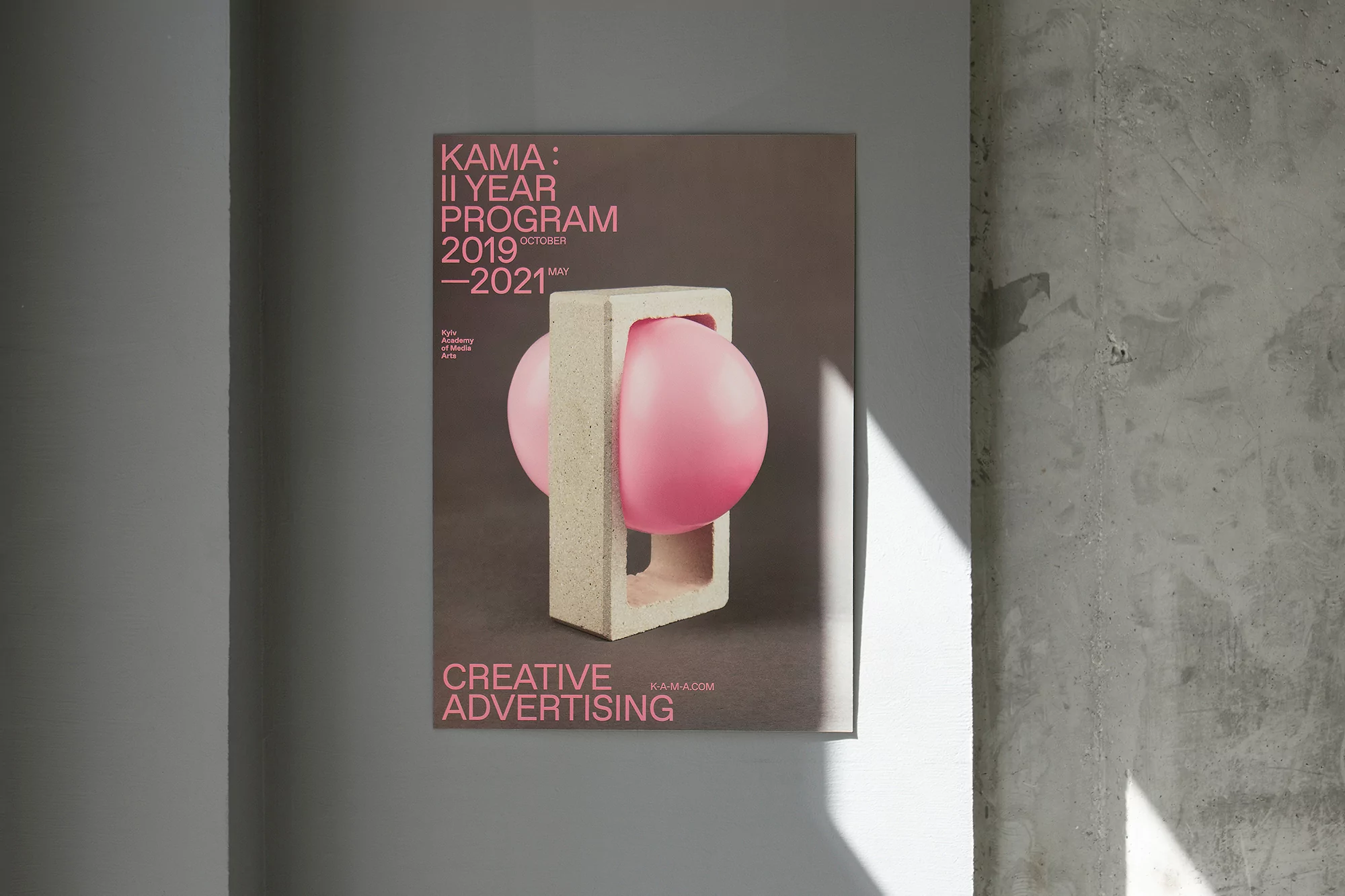 Poster on a concrete wall showcases a contemporary design featuring a pink sphere held within a minimalist geometric concrete form.