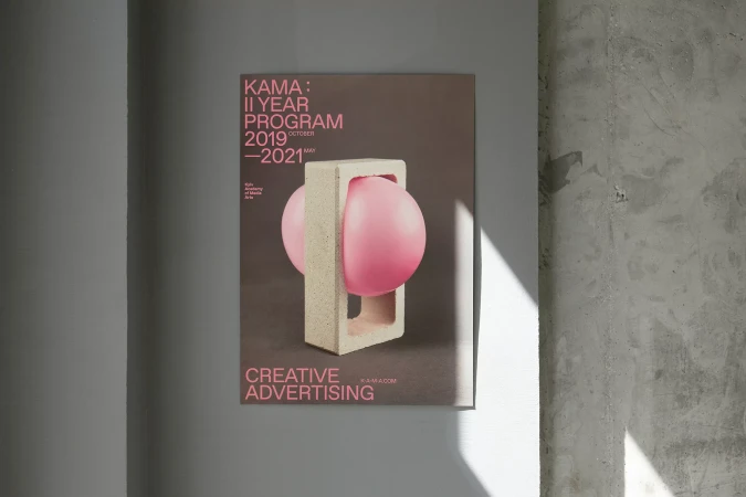 Poster on a concrete wall showcases a contemporary design featuring a pink sphere held within a minimalist geometric concrete form.