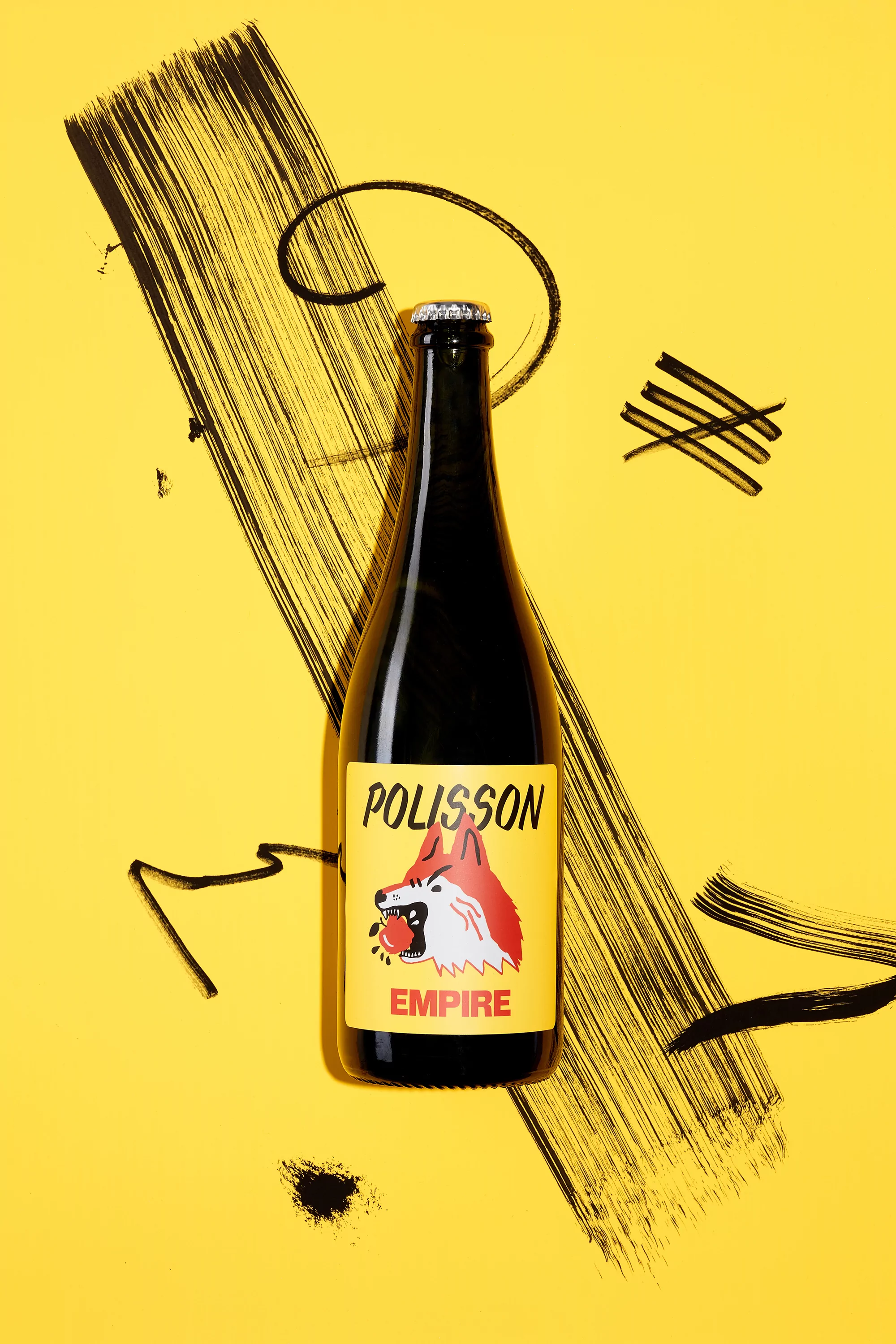 Artistic product shot of a dark glass beer bottle with a fox logo label on a yellow surface with black paint strokes around it.