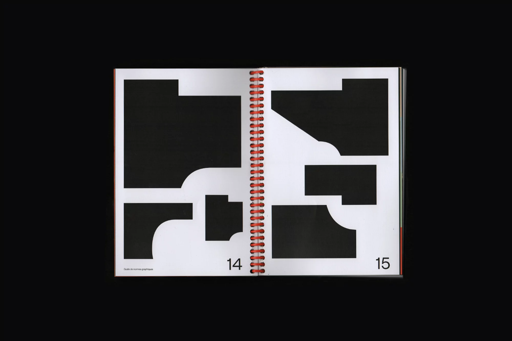 An open book with black geometric shapes on white pages and a red spiral binding, set against a black background.