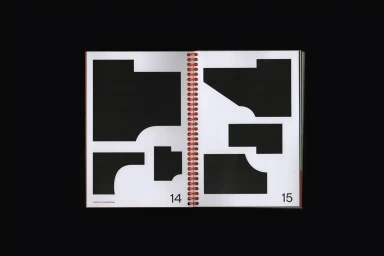 Open spiral-bound graphic design book displaying abstract black shapes on white pages against a dark background