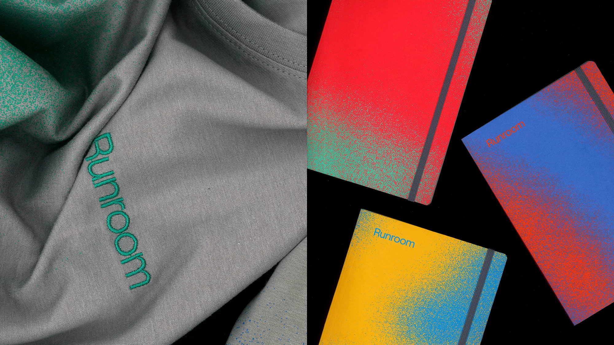 Still life shot of a folded gray shirt with a logo next to colorful notebooks with matching logo, on a black background.