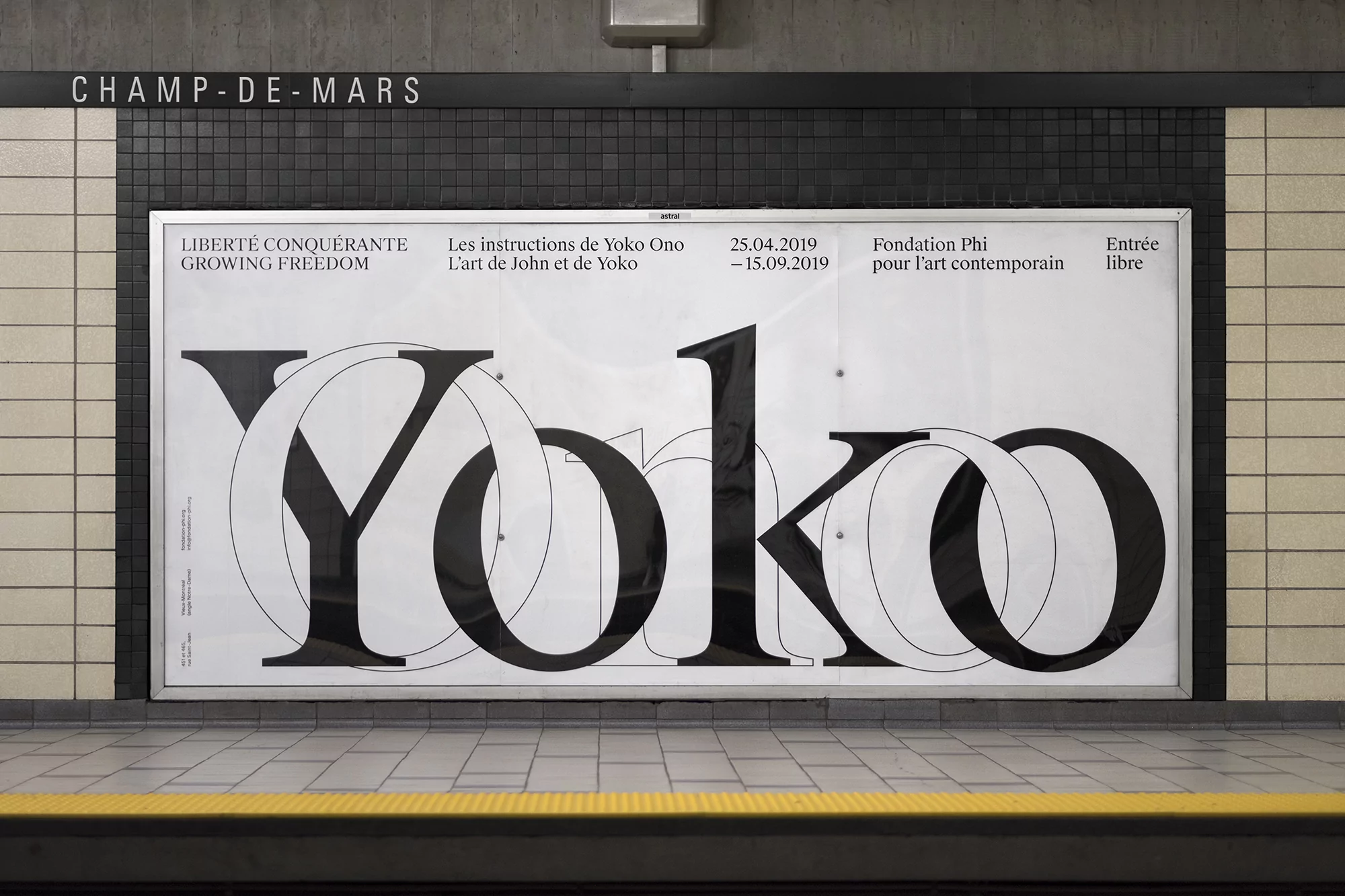 Large black and white typographic art poster in an indoor public space, featuring the name 'Yoko' in bold, overlapping letters.